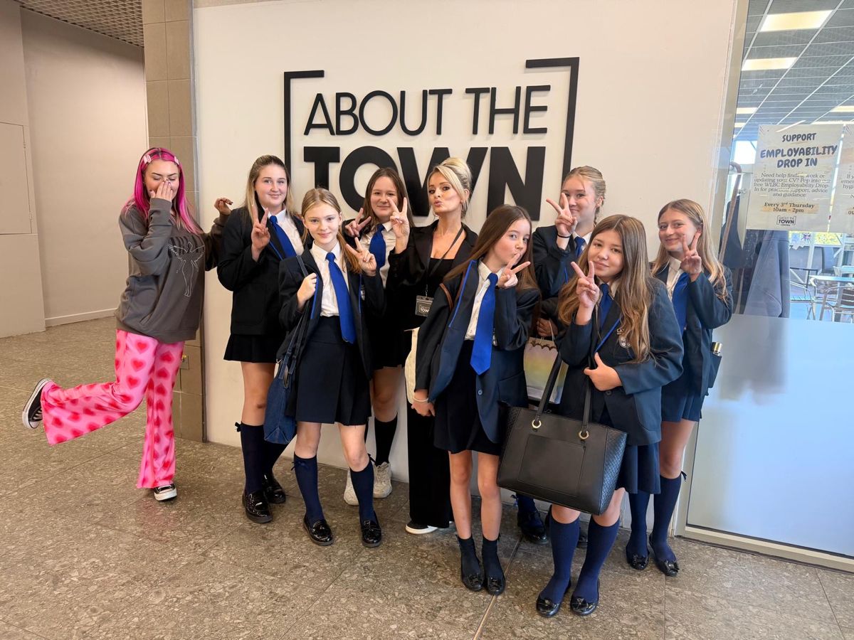 Bev with #HashtagGirls participants in front of the About the Town sign
