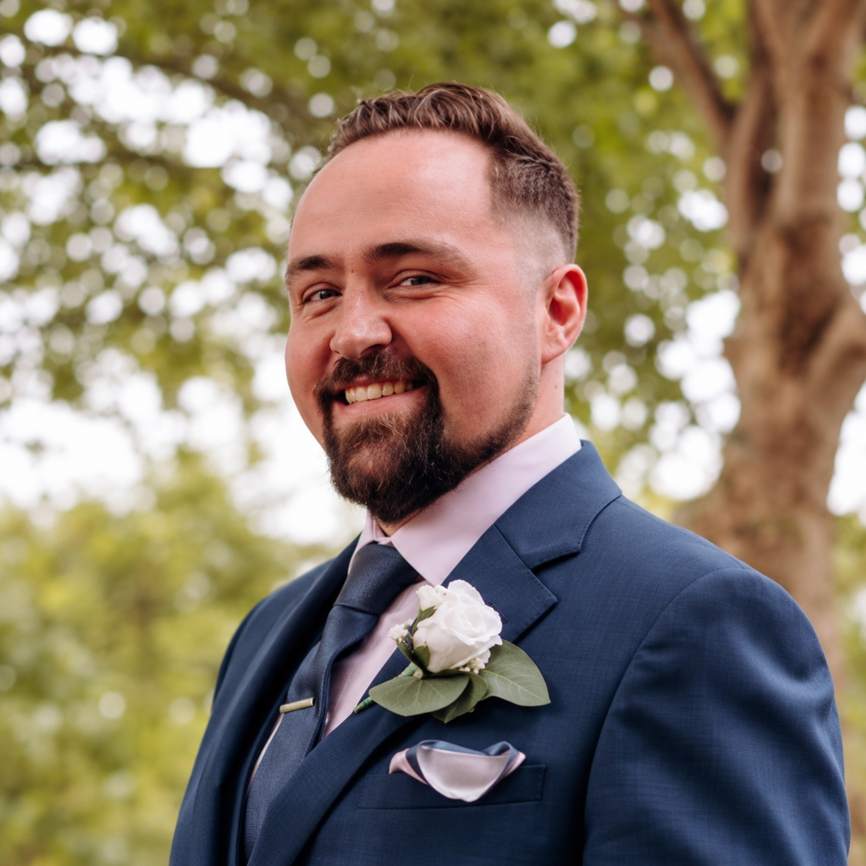 Leon Taraldsen smiling in a navy suit with a white rose buttonhole