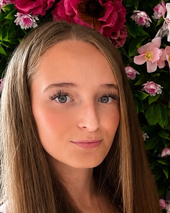 Isobelle smiling in front of a flower wall