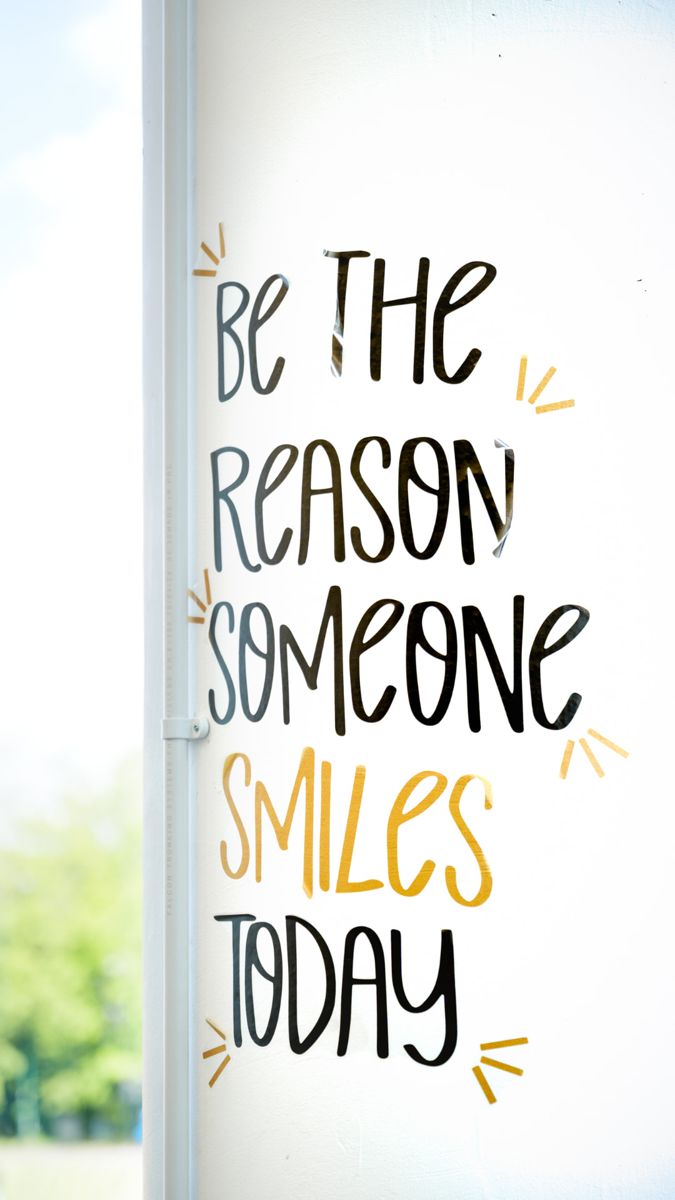 Hand-lettered wall sign reading “Be the reason someone smiles today”